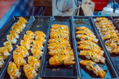 Sıra sıra Japon suşi yemekleri. Maki ve rulo ton balığı, somon, karides, yengeç ve avokado. Markette satılan siyah plastik konteynırdaki çeşitli suşilerin üst görüntüsü. Seçici odak.