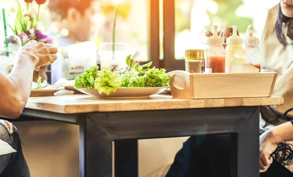 Happiness woman and friend talk and eat salads on the table in restaurant. Selective focus on lettuce.