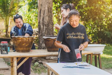 LAMPHUN THAILAND - 12 ARALIK: tanımlanamayan Taylandlı kadın turistler, Tayland 'ın Lamphun kentindeki Karen köyünde 12 Aralık 2019 tarihinde kravat boyası yapmayı öğreniyorlar.