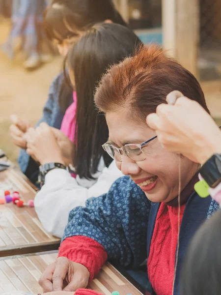 TAILANDIA DE LÁMFONO - 12 DE DICIEMBRE: Turistas tailandesas no identificadas aprenden a hacer un collar de una bola de hilado el 12 de diciembre de 2019 en la aldea Karen en Lamphun, Tailandia — Foto de Stock