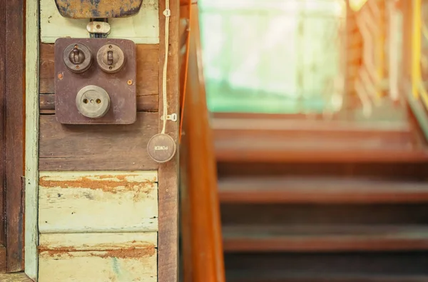 Proche d'une très vieille lampe électrique rétro allumée sur une planche en bois. Commutateur vintage, mise au point sélective — Photo