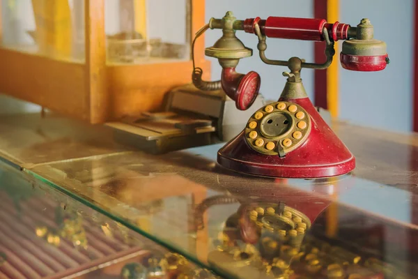 Červené telefony s otočným ciferníkem s prachem a škrábanci a kreditní kartou v dávných dobách umístěné na skleněné vitríně ve starém zlatnictví v Asii. — Stock fotografie