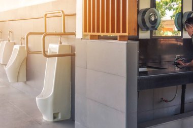 Engelli ya da paslanmaz çelik saplı yaşlı insanlar için dost tasarımı olan temiz ve modern kamu erkekler tuvaleti ve benzin istasyonunda otomatik sensör sifonlu beyaz seramik sidik torbaları. Paslanmaz çelik kulplara odaklan.