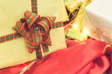 Farklı boyutlarda ve şekillerde güzel hediye kutuları ve hediyeler. Masada kurdele var.