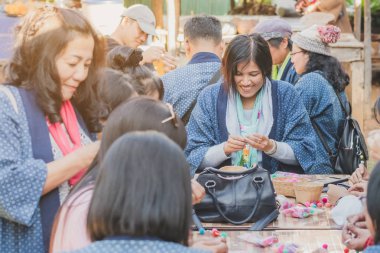 Tanımlanamayan Tayland 'lı kadın turistler, Tayland' ın Lamphun kentindeki Karen köyünde 12 Aralık 2019 tarihli iplik balosundan kolye yapmayı öğreniyor.