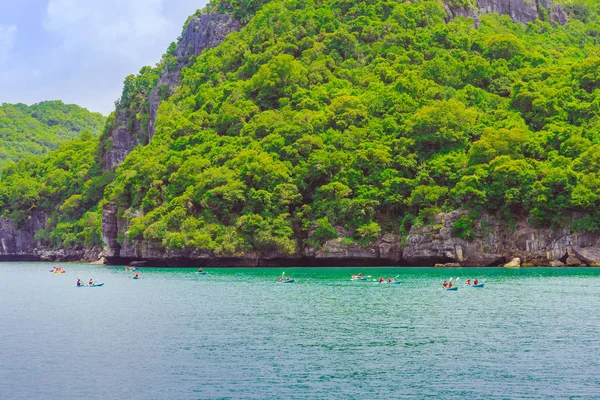 ANG THONG MARINE PARK, SAMUI, THAILAND - OCTOBER 13,2019 : Tourists kayaking in blue Idyllic turquoise ocean to explore near the island with lush green jungle trees and lime stone mountains at Ang Thong National Marine Park, Thailand. — Stock Photo, Image