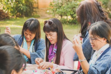 Tanımlanamayan Tayland 'lı kadın turistler, Tayland' ın Lamphun kentindeki Karen köyünde 12 Aralık 2019 tarihli iplik balosundan kolye yapmayı öğreniyor.