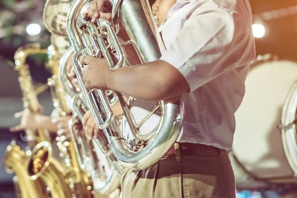 Estudante do sexo masculino com amigos soprar o eufônio com a banda para o desempenho no palco à noite . — Fotografia de Stock