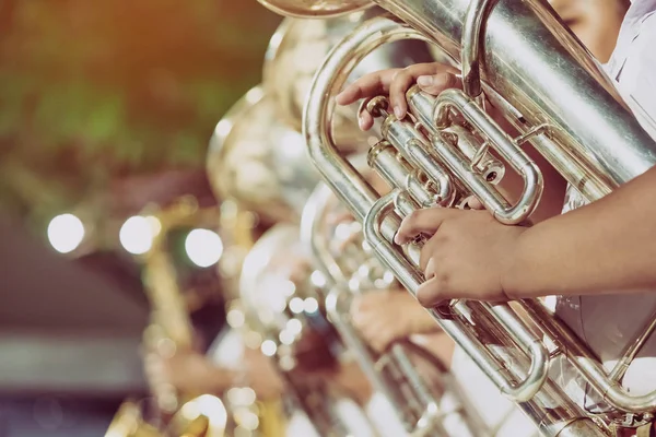 Studente maschio con gli amici soffiano l'eufonia con la band per la performance sul palco di notte . — Foto Stock