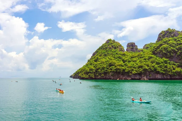 ANG THONG MARINE PARK, SAMUI, TAILANDIA - 13 DE OCTUBRE DE 2019: Turistas navegando en kayak en azul Océano turquesa idílico para explorar cerca de la isla con exuberantes árboles de selva verde y montañas de piedra caliza en el Parque Nacional Marino Ang Thong, Tailandia . — Foto de Stock