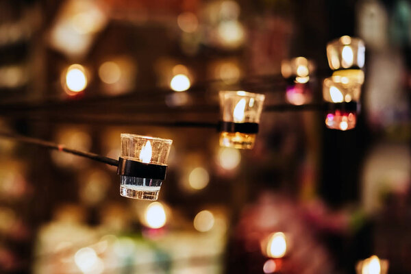 A Burning Candle in Clear Glass stick with steel rod Decorated in Hotel, Restaurant or Home. Selective Focus, Blurred Background with Bokeh.