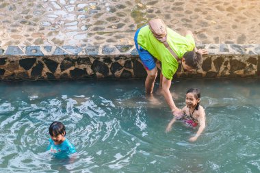 KANCHANABURI, THAILAND - 1 Ocak 2020 'de Kanchanaburi, Tayland' da kimliği belirlenemeyen Asyalı turistler cesedi sıcak maden suyuna batırıp sağlık için Hindad Hotspring 'te yıkandılar..