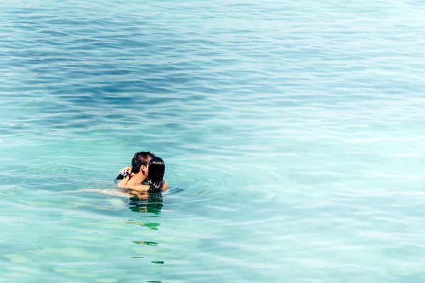 Jovem homem forte no amor abraçando e abraçando girlgriend em um terno de biquíni no mar. Belo casal no mar . — Fotografia de Stock