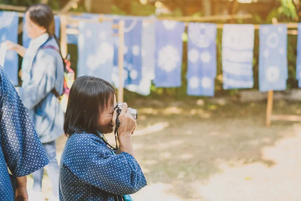 TAILANDIA DE LÁNFUN - 12 DE DICIEMBRE: Turista tailandesa no identificada TAILANDIA DE LÁNFUN - 12 DE DICIEMBRE: Turista tailandesa no identificada toma una fotografía mientras sus amigas aprenden a hacer ropa de tinte de corbata el 12 de diciembre de 2019 en la aldea Karen en Lamphun, Tailandia — Foto de Stock