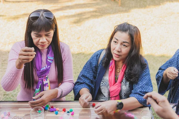 TAILANDIA DE LÁMFONO - 12 DE DICIEMBRE: Turistas tailandesas no identificadas aprenden a hacer un collar de una bola de hilado el 12 de diciembre de 2019 en la aldea Karen en Lamphun, Tailandia — Foto de Stock