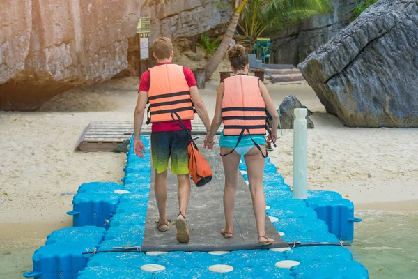 Miłośnicy pary trzymając się za ręce, spacerując po plastikowym pontonie, idą na plażę.. — Zdjęcie stockowe