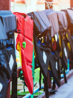 Rıhtımdaki yolcuların güvenliği için korkuluklara asılı kırmızı can yeleği olan yeşil bir düdük..