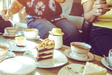 Mutlu bayan arkadaşlar, öğleden sonra kafede birlikte çay ya da kahve içerek buluşuyorlar. İnsanlar, eğlence ve iletişim konsepti. Seçici odak.