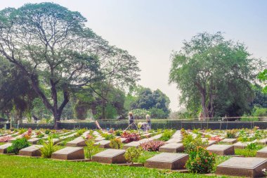 KANCHANABURI THAILAND - 21 Şubat: Kimliği belirsiz işçiler, 21 Şubat 2020 'de Kanchanaburi, Tayland' daki Kanchanaburi Müttefik Savaş Mezarlığı 'nda çiçek yenileyip dekore ediyorlar