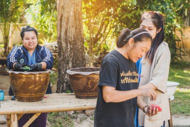LAMPHUN THAILAND - 12 ARALIK: tanımlanamayan Taylandlı kadın turistler, Tayland 'ın Lamphun kentindeki Karen köyünde 12 Aralık 2019 tarihinde kravat boyası yapmayı öğreniyorlar.