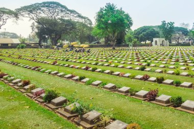 KANCHANABURI THAILAND - 21 Şubat: Kimliği belirsiz işçiler, 21 Şubat 2020 'de Kanchanaburi, Tayland' daki Kanchanaburi Müttefik Savaş Mezarlığı 'nda çiçek yenileyip dekore ediyorlar