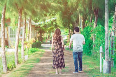 Halk parkındaki çam ağaçlarının altında yürüyen ve fotoğraf çeken çift..