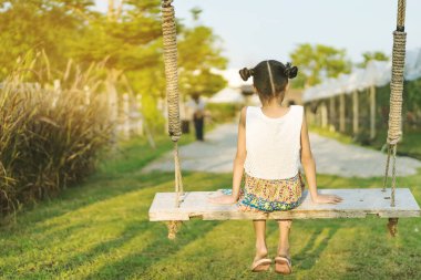 Salıncakta sallanan genç kızın arkası görünüyor. Annesini organik üzüm çiftliğinde bekliyor..