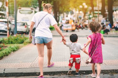 Güneşli bir yaz gününde, küçük oğluyla birlikte kaldırımda yürüdüğü arka manzara.