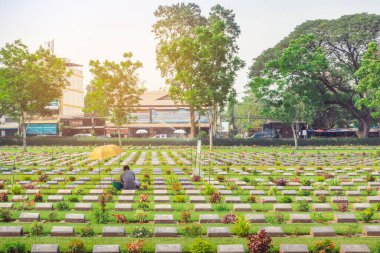 KANCHANABURI THAILAND - 21 Şubat: Kimliği belirsiz işçiler, 21 Şubat 2020 'de Kanchanaburi, Tayland' daki Kanchanaburi Müttefik Savaş Mezarlığı 'nda çiçek yenileyip dekore ediyorlar