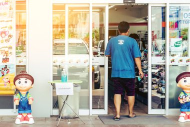 KANCHANABURI THAILAND - 22 Mart 2020 'de Kanchanaburi, Tayland' da 7-Eleven bakkal önünde müşterilere hizmet veren grip virüsünün önlenmesi için el yıkama jeli dezenfektanı.