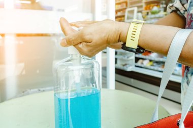 Kadın, şehirde elini temizlemek için el dezenfektanı şişesine basıyor. Grip virüsü, Covid-19 (Coronavirus hastalığı). Alkol jeli şişesine odaklan.