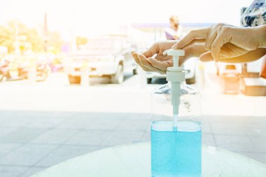 Kadın, şehirde elini temizlemek için el dezenfektanı şişesine basıyor. Grip virüsü, Covid-19 (Coronavirus hastalığı). Alkol jeli şişesine odaklan.