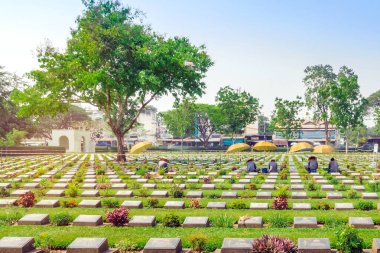 KANCHANABURI THAILAND - 21 Şubat: Kimliği belirsiz işçiler, 21 Şubat 2020 'de Kanchanaburi, Tayland' daki Kanchanaburi Müttefik Savaş Mezarlığı 'nda çiçek yenileyip dekore ediyorlar