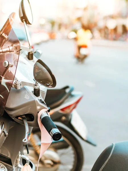 A mask hanging on a motorcycle handle to prevent germs (Covid-19) on roadside in the city. Corona virus protection concept.