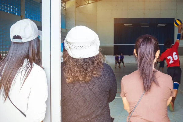 Back view of asian parents cheering childrens learn to playing volleyball in school.