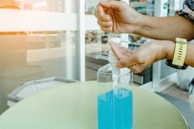 Kadın, şehirde elini temizlemek için el dezenfektanı şişesine basıyor. Grip virüsü, Covid-19 (Coronavirus hastalığı). Alkol jeli şişesine odaklan.