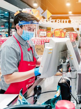 KANCHANABURI, THAILAND - 6 Nisan 2020: Kanchanaburi, Tayland 'daki Top Supermarket' te mikropların (Covid-19) yayılmasını önlemek için tanımlanamayan kasiyer veya süpermarket personeli ve tıbbi koruyucu maskeli müşteriler.