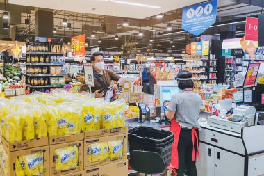KANCHANABURI, THAILAND - 6 Nisan 2020: Kanchanaburi, Tayland 'daki Top Supermarket' te mikropların (Covid-19) yayılmasını önlemek için tanımlanamayan kasiyer veya süpermarket personeli ve tıbbi koruyucu maskeli müşteriler.