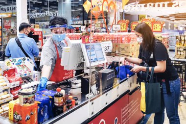KANCHANABURI, THAILAND - 6 Nisan 2020: Kanchanaburi, Tayland 'daki Top Supermarket' te mikropların (Covid-19) yayılmasını önlemek için tanımlanamayan kasiyer veya süpermarket personeli ve tıbbi koruyucu maskeli müşteriler.