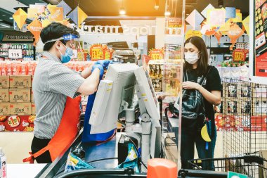 KANCHANABURI, THAILAND - 6 Nisan 2020: Kanchanaburi, Tayland 'daki Top Supermarket' te mikropların (Covid-19) yayılmasını önlemek için tanımlanamayan kasiyer veya süpermarket personeli ve tıbbi koruyucu maskeli müşteriler.