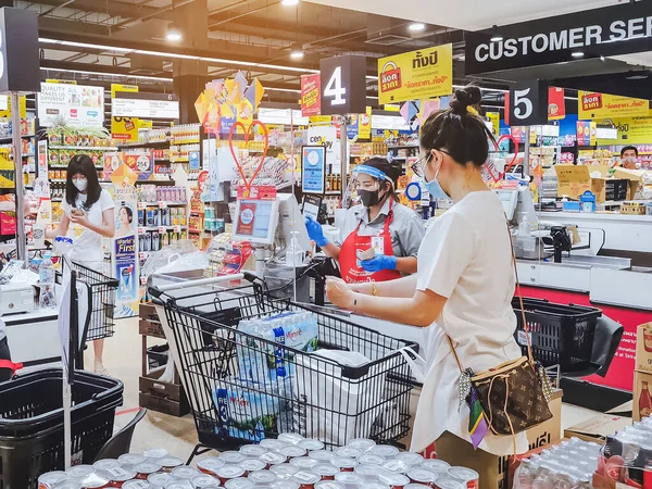KANCHANABURI, THAILAND - 6 Nisan 2020: Kanchanaburi, Tayland 'daki Top Supermarket' te mikropların (Covid-19) yayılmasını önlemek için tanımlanamayan kasiyer veya süpermarket personeli ve tıbbi koruyucu maskeli müşteriler.