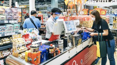 KANCHANABURI, THAILAND - 6 Nisan 2020: Kanchanaburi, Tayland 'daki Top Supermarket' te mikropların (Covid-19) yayılmasını önlemek için tanımlanamayan kasiyer veya süpermarket personeli ve tıbbi koruyucu maskeli müşteriler.