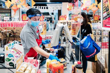 KANCHANABURI, THAILAND - 6 Nisan 2020: Kanchanaburi, Tayland 'daki Top Supermarket' te mikropların (Covid-19) yayılmasını önlemek için tanımlanamayan kasiyer veya süpermarket personeli ve tıbbi koruyucu maskeli müşteriler.