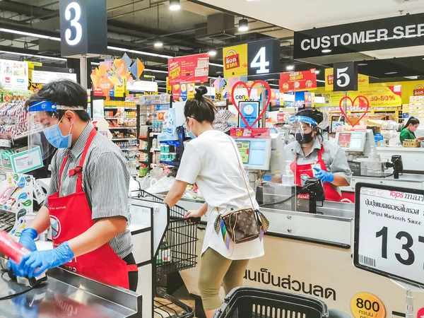 KANCHANABURI, THAILAND - 6 Nisan 2020: Kanchanaburi, Tayland 'daki Top Supermarket' te mikropların (Covid-19) yayılmasını önlemek için tanımlanamayan kasiyer veya süpermarket personeli ve tıbbi koruyucu maskeli müşteriler.