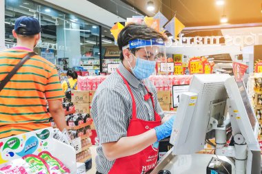 KANCHANABURI, THAILAND - 6 Nisan 2020: Kanchanaburi, Tayland 'daki Top Supermarket' te mikropların (Covid-19) yayılmasını önlemek için tanımlanamayan kasiyer veya süpermarket personeli ve tıbbi koruyucu maskeli müşteriler.