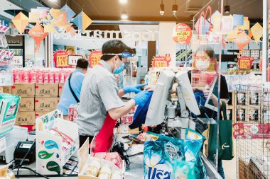 KANCHANABURI, THAILAND - 6 Nisan 2020: Kanchanaburi, Tayland 'daki Top Supermarket' te mikropların (Covid-19) yayılmasını önlemek için tanımlanamayan kasiyer veya süpermarket personeli ve tıbbi koruyucu maskeli müşteriler.