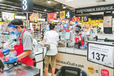 KANCHANABURI, THAILAND - 6 Nisan 2020: Kanchanaburi, Tayland 'daki Top Supermarket' te mikropların (Covid-19) yayılmasını önlemek için tanımlanamayan kasiyer veya süpermarket personeli ve tıbbi koruyucu maskeli müşteriler.