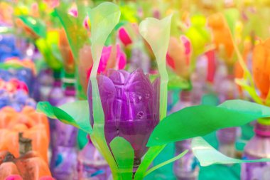 Plastik şişelerden yapılmış renkli plastik çiçekler bahçedeki çiçek süsü olarak kullanılıyor. Plastik şişe geri dönüştürüldü.