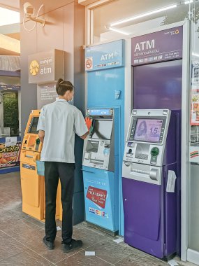 KANCHANABURI, THAILAND - 12 Nisan 2020: Tayland 'da Kanchanaburi, Tayland' da 12 Nisan 2020 'de 7-Eleven' ın önünde Corona virüsüne karşı önleyici tedbirler almak için alkollü tanımlanamayan erkek memur temiz ATM.
