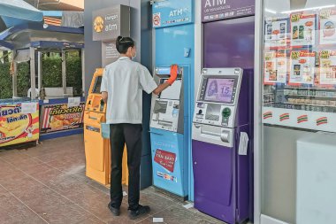 KANCHANABURI, THAILAND - 12 Nisan 2020: Tayland 'da Kanchanaburi, Tayland' da 12 Nisan 2020 'de 7-Eleven' ın önünde Corona virüsüne karşı önleyici tedbirler almak için alkollü tanımlanamayan erkek memur temiz ATM.